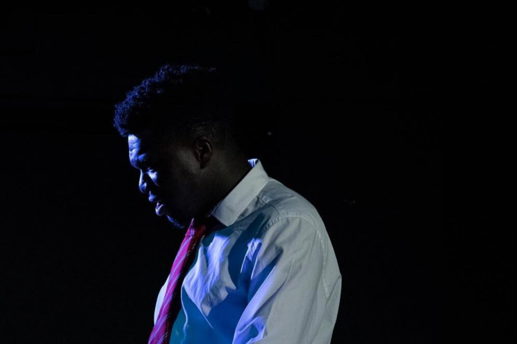 Actor in a white shirt and pink tie on stage